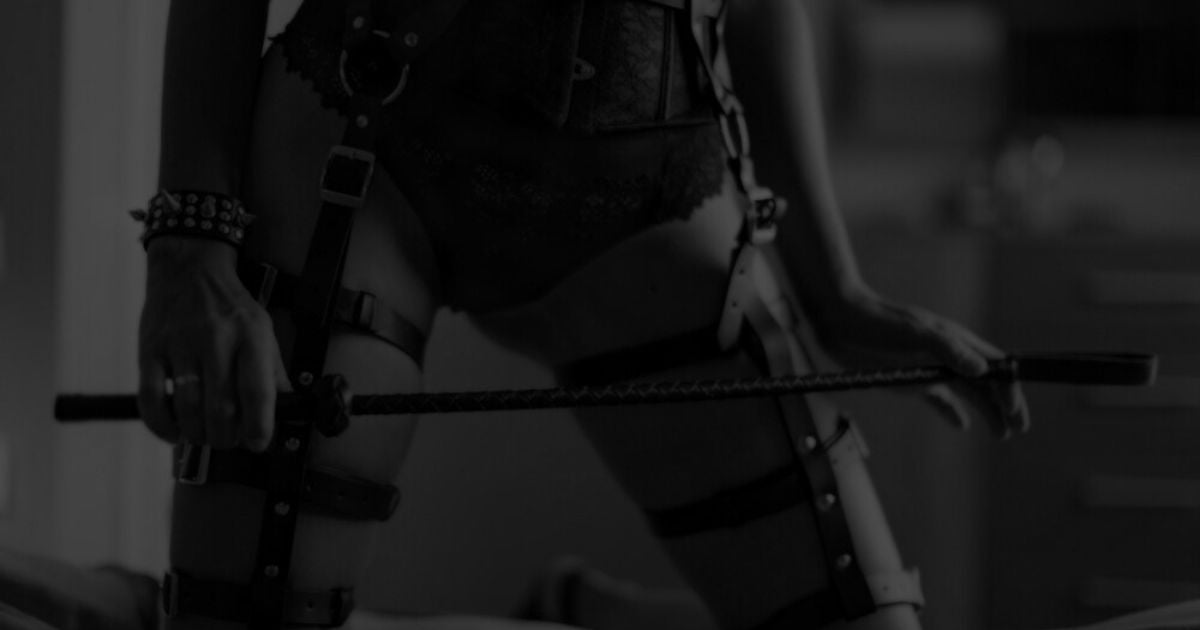 Personne en harnais de cuir et lingerie tenant une cravache Imagen