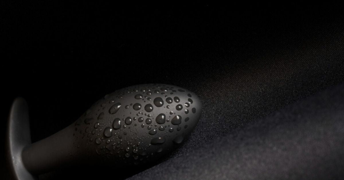 Plug anal en métal poli couvert de gouttes d'eau sur fond noir